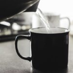 Donna che beve acqua calda, simbolo di salute e digestione attiva.